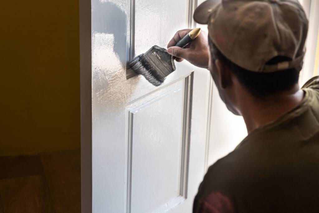 person painting wooden white door with paint brush 2023 11 27 05 06 19 utc