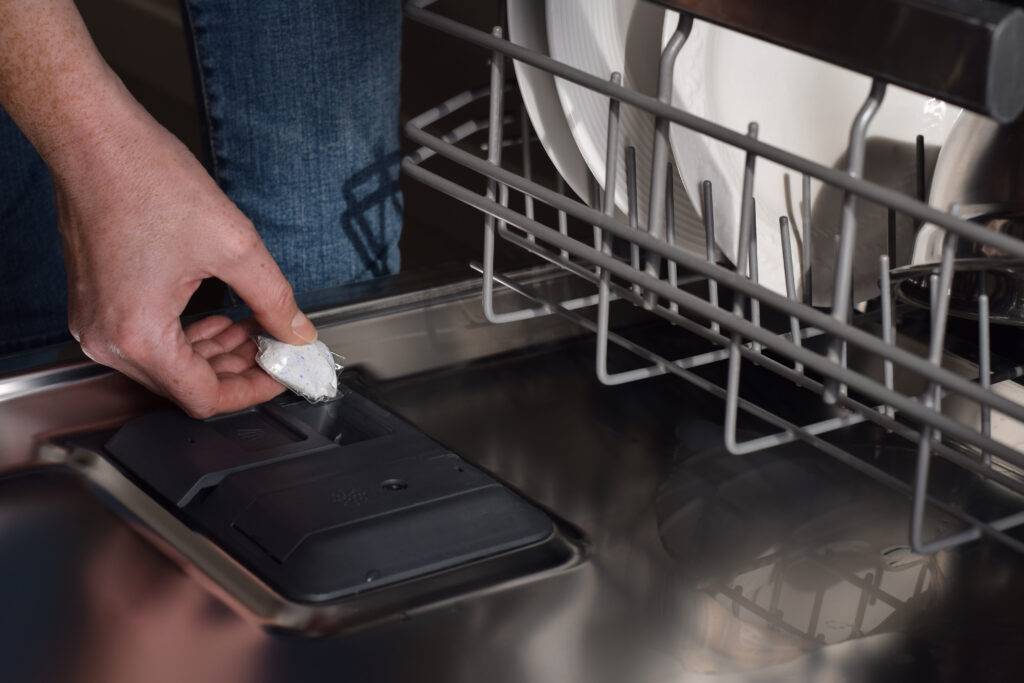 woman placing detergent pod into dishwasher soap d 2023 11 27 05 36 04 utc